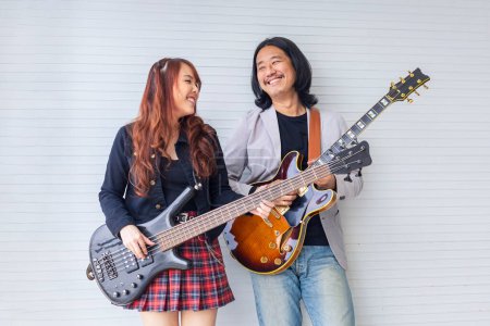 Photo for Portrait of Asian family duo rock band of young girl idol on bassist and male on semi hollow electric guitar standing on white background for music, artist, musician - Royalty Free Image