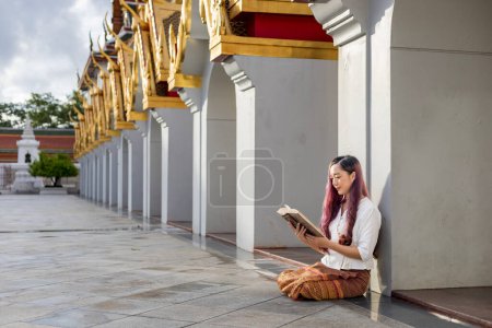 Asiatische buddhistische Frau liest Sanskrit altes Tripitaka Buch von Lord Buddha dhamma Lehre, während sie im Tempel sitzt, um im Kloster zu singen und anzubeten