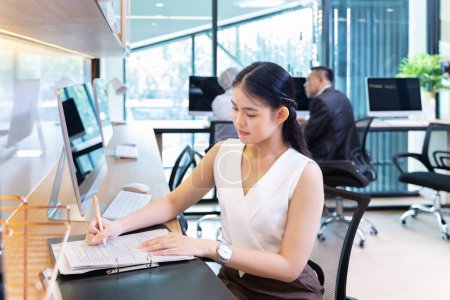 Téléchargez les photos : Femme d'affaires asiatique en costume formel travaillant dans un bureau de luxe moderne utilisant l'ordinateur pour les affaires et l'éducation - en image libre de droit