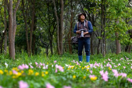 Foto de Fotógrafo está tomando fotos mientras explora en el bosque con prado de flores silvestres para estudiar y localizar la rara diversidad biológica y ecologista en el estudio de campo - Imagen libre de derechos