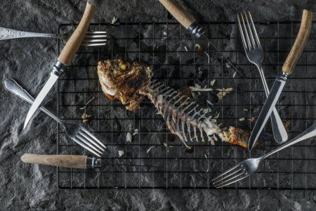 Photo for Bones left after eating grilled Dorado on dark textured background. Healthy eating concept. Seafood recipes - Royalty Free Image