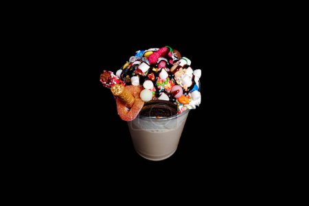 Photo for Organic cocoa drink or chocolate milkshake with topping of marshmallow and caramel syrup served in drinking glass with straw  and candies on black background. - Royalty Free Image