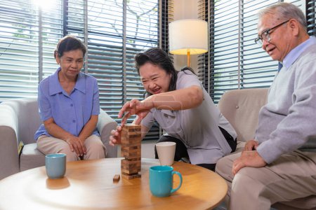 Téléchargez les photos : Des amis âgés construisent la tour à partir de cubes en bois temps libre dans une maison de retraite
. - en image libre de droit