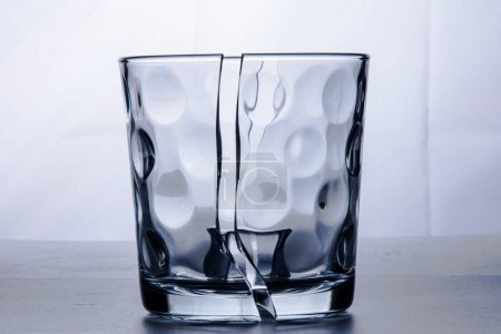 Foto de Vidrio roto en dos mitades con un cubo de hielo. Fotografiado sobre fondo blanco en estudio. Bodegón. - Imagen libre de derechos