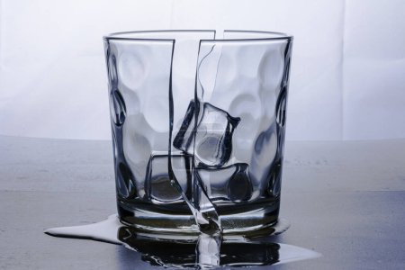 Foto de Vidrio roto en dos mitades con tres cubos de hielo. Fotografiado sobre fondo blanco en estudio. Retroiluminación naturaleza muerta. - Imagen libre de derechos