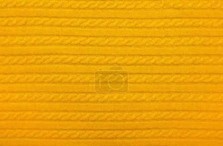 Photo for Close up background texture of warm yellow cable knitted wool jersey fabric sweater with row braid pattern - Royalty Free Image