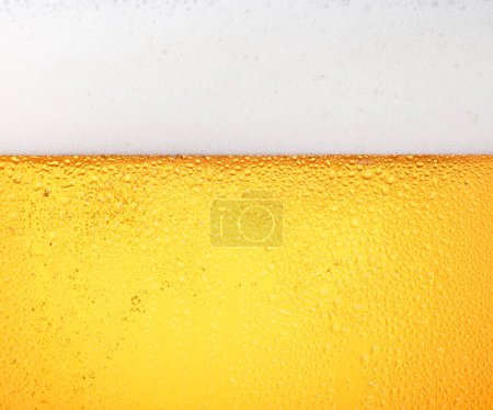 Foto de Textura de fondo de verter cerveza lager con burbujas y espuma en vidrio esmerilado con gotas, vista lateral de bajo ángulo - Imagen libre de derechos