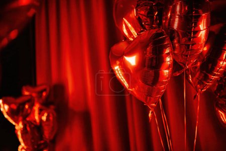 Photo for Extravagant bedroom luxury interior with love glamour decoration at Valentines day in studio. Party lettering and balloons by heart shaped and at illuminated mirror romantic cozy atmosphere at red background. - Royalty Free Image