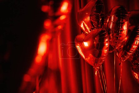 Photo for Extravagant bedroom luxury interior with love glamour decoration at Valentine day in studio. Balloons by heart shaped and at illuminated mirror romantic cozy atmosphere at vivid red background. - Royalty Free Image