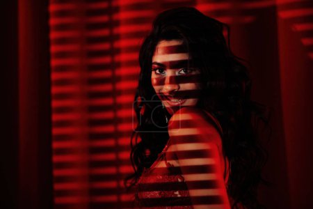 Foto de Sexy mujer asiática en ropa interior de encaje bajo la luz y la sombra de persianas en rojo glamour fondo - Imagen libre de derechos