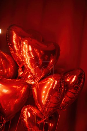 Photo for Extravagant bedroom luxury interior with love glamour decoration at Valentines day in studio. Balloons by heart shaped and at illuminated mirror romantic cozy atmosphere at vivid red background. - Royalty Free Image