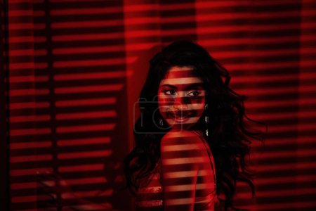 Foto de Sexy asian woman in lace underwear under light and shadow of blinds at red glamour background - Imagen libre de derechos