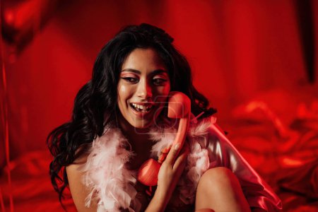 Photo for Close up portrait of sexy asian sensual model in red lace underwear and feather boa posing with pink vintage telephone - Royalty Free Image