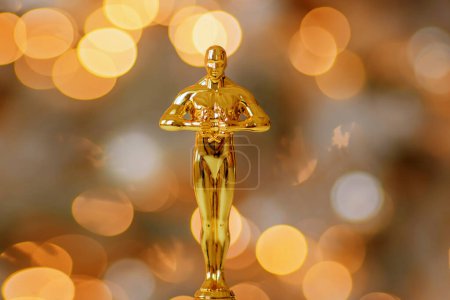 Foto de Hollywood gold oscars trophy figurine imitation seen during an award cinema ceremony. Success and victory concept close up statuette at twinkle yellow lights background - Imagen libre de derechos