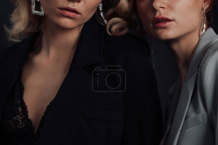 Photo for Adult beauty elegant multi ethnic young girls in formal evening suits of different colors with bra. Stylish blonde and redhead sensual fashionistas posing at studio in fashion pantsuits no shirts - Royalty Free Image