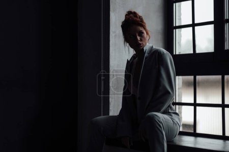 Photo for Adult beauty elegant young woman in formal evening gray suit with white bra at thoughtful. Stylish ginger curly hair sensual model bare shoulder fashionista posing at studio in fashion pantsuit - Royalty Free Image