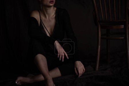 Adult beauty elegant young woman in formal evening black clothing hand on face touching. Stylish ginger curly hair sensual model bare shoulder fashionista posing at studio in fashion pantsuit and bra