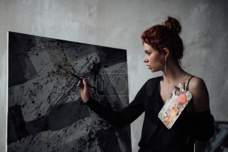 Photo for Adult beauty elegant young woman in formal evening black blouse. Stylish ginger curly hair sensual model bare shoulder fashionista posing with paint palette and brushe hugs painting rolls at studio - Royalty Free Image