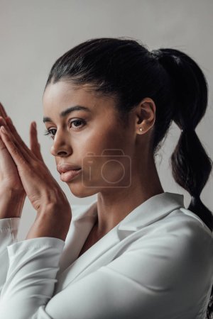 Young adult beauty swarthy woman in formal evening white suit no shirt hand on face touching. Stylish black curly hair sensual african american model fashionista posing at studio in fashion pantsuit