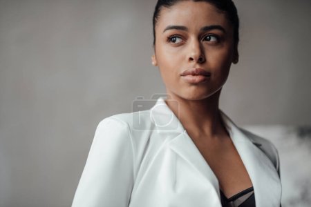 Photo for Young adult beauty swarthy woman in formal evening white suit with bra at thoughtful. Stylish black curly hair sensual african american model fashionista posing at studio in fashion pantsuit - Royalty Free Image