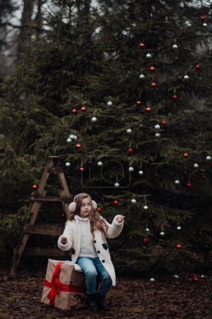 Téléchargez les photos : Enfant féminin célébrant Noël et Nouvel An saison des vacances d'hiver en plein air. Petite fille active joyeuse passer du temps dans la forêt de conifères profiter de l'enfance - en image libre de droit