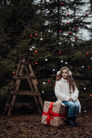 Photo for Active little girl rest at forest enjoying childhood decorating balls Xmas tree. Female child celebrating Christmas and New Year winter holidays season outdoor - Royalty Free Image