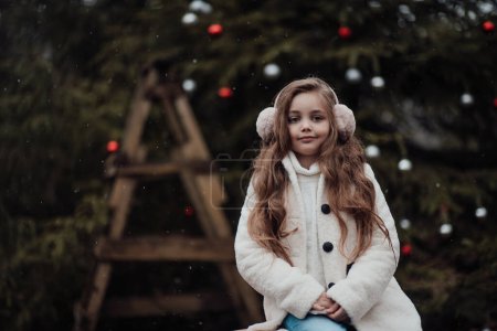 Photo for Active little girl rest at forest enjoying childhood decorating balls Xmas tree. Female child celebrating Christmas and New Year winter holidays season outdoor - Royalty Free Image