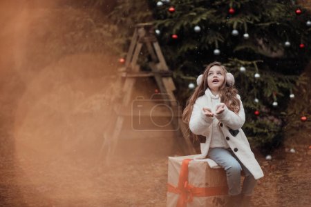 Photo for Female child celebrating Christmas and New Year winter holidays season outdoor. Active little girl joyful spending time at coniferous forest enjoying childhood - Royalty Free Image