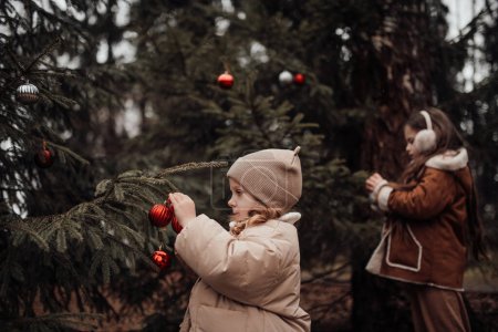 Téléchargez les photos : Enfants féminins célébrant Noël et Nouvel An saison des vacances d'hiver en plein air. Enfants actifs joyeux passer du temps ensemble s'amuser près de Noël bus se réjouit à la première neige profiter de l'enfance - en image libre de droit