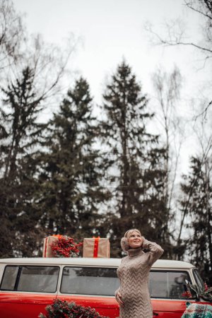 Téléchargez les photos : Souriant actif repos de la femme enceinte se détendre en profitant froid givré temps neigeux en attendant la naissance de l'enfant.Célébration de Noël et du Nouvel An saison des vacances d'hiver à l'extérieur dans la forêt près de Noël vieux bus rouge - en image libre de droit