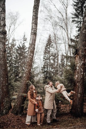Photo for Happy family celebrating Christmas and New Year winter holidays season outdoor. Kids with parents joyful spending time together hugging having fun at forest stroll - Royalty Free Image