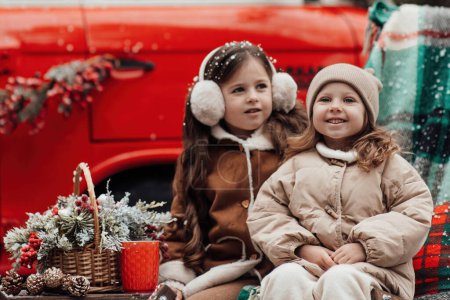 Téléchargez les photos : Petites filles célébrant Noël et Nouvel An saison des vacances d'hiver en plein air. Petites filles actives joyeuses passer du temps dans la forêt de conifères profiter de l'enfance - en image libre de droit