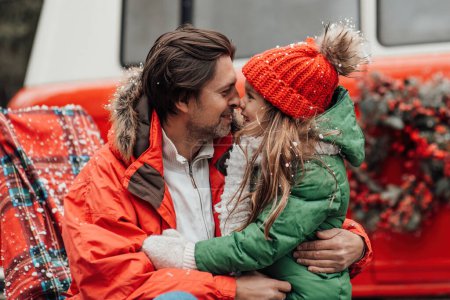 Photo for Happy family celebrating Christmas and New Year winter holidays season outdoor. Father with little daughter joyful spending time together hugging having fun near Xmas bus rejoices at first snow - Royalty Free Image