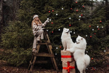 Foto de Niña celebrando Navidad y Año Nuevo vacaciones de invierno temporada al aire libre. Niña alegre pasar tiempo al aire libre con perros Samoyedo blancos cerca de autobús de Navidad disfrutando de la infancia - Imagen libre de derechos