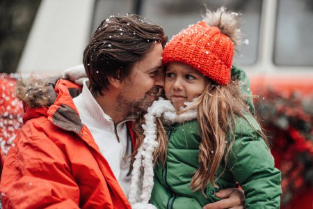 Photo for Happy family celebrating Christmas and New Year winter holidays season outdoor. Father with little daughter joyful spending time together hugging having fun near Xmas bus rejoices at first snow - Royalty Free Image