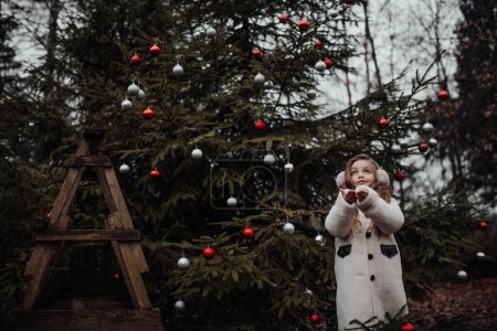 Foto de Niña celebrando Navidad y Año Nuevo vacaciones de invierno temporada al aire libre. Chica activa alegre pasar tiempo en el bosque de coníferas disfrutando de la infancia - Imagen libre de derechos