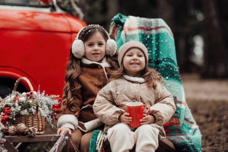 Photo for Little girls celebrating Christmas and New Year winter holidays season outdoor. Active little girls joyful spending time at coniferous forest enjoying childhood - Royalty Free Image