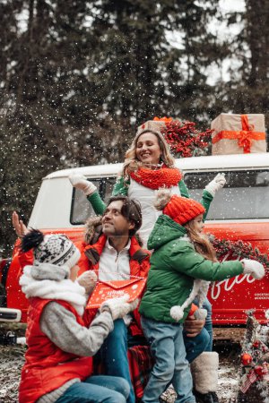 Foto de Feliz familia celebrando Navidad y Año Nuevo vacaciones de invierno temporada al aire libre. Niños activos con padres alegres pasar tiempo juntos abrazar divertirse cerca de autobús de Navidad se regocija en la primera nieve - Imagen libre de derechos