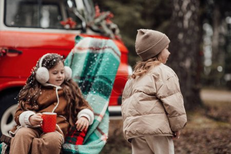 Photo for Little girls celebrating Christmas and New Year winter holidays season outdoor. Active little girls joyful spending time at coniferous forest enjoying childhood - Royalty Free Image