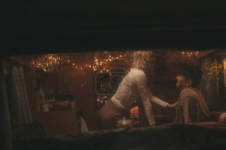 Photo for Happy couple celebrating Christmas and New Year winter holidays season in Camper Park. Young couple rest spending time together hugs and kisses in window of Xmas camper trailer - Royalty Free Image
