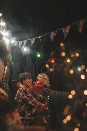 Foto de Pareja feliz celebrando Navidad y Año Nuevo temporada de vacaciones de invierno en Camper Park. Jóvenes pareja de descanso y relajación pasar tiempo juntos abrazos y besos cerca de la Navidad caravana remolque - Imagen libre de derechos