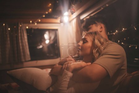 Photo for Happy couple celebrating Christmas and New Year winter holidays season in camper. Young couple joyful spending time together having fun pillow fight in Xmas camper trailer - Royalty Free Image