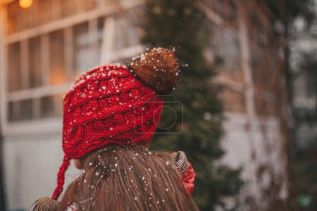 Téléchargez les photos : Vue arrière de la petite fille célébrant Noël et le Nouvel An saison des vacances d'hiver en plein air, attendant Santa près de caravane camping-car de Noël et se réjouit à la première neige profiter de l'enfance - en image libre de droit