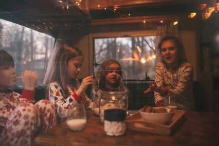 Kinder, die Weihnachten und Neujahr feiern, warten im Wohnmobil auf den Weihnachtsmann. Kinder verbringen Zeit mit Grimasse, trinken Milch und genießen Zuckerrohr und Plätzchen im Wohnwagen zu Weihnachten