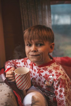 Foto de Niño bebe leche mientras celebra Navidad y Año Nuevo temporada de vacaciones de invierno y espera a Santa en la caravana de Navidad - Imagen libre de derechos