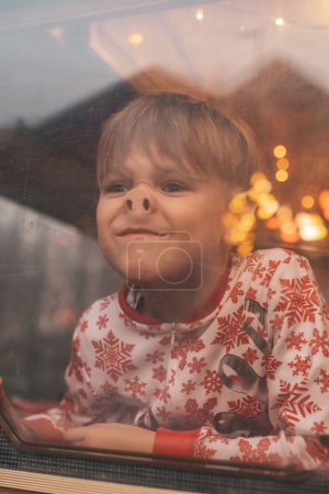 Photo for Little boy making faces while celebrating Christmas and New Year winter holidays season waiting Santa at Xmas camper trailer - Royalty Free Image