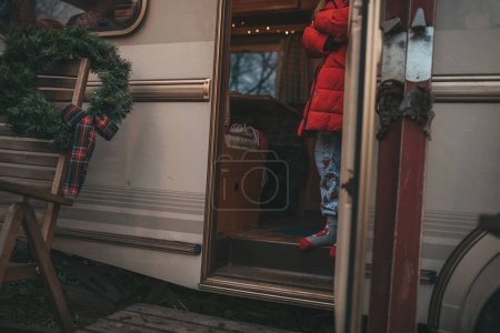 Téléchargez les photos : Petite fille célébrant Noël et Nouvel An saison des vacances d'hiver et attendant le Père Noël au camping-car de Noël remorque. - en image libre de droit