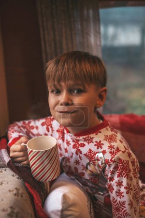Photo for Little boy drinks milk while celebrating Christmas and New Year winter holidays season and waiting Santa at Xmas camper trailer - Royalty Free Image