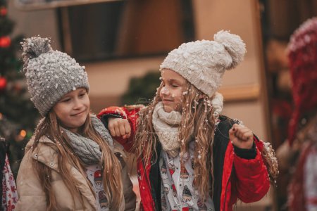 Photo for Girls celebrating Christmas and New Year winter holidays season outdoor. Little girls joyful spending time together near Xmas camper trailer. - Royalty Free Image