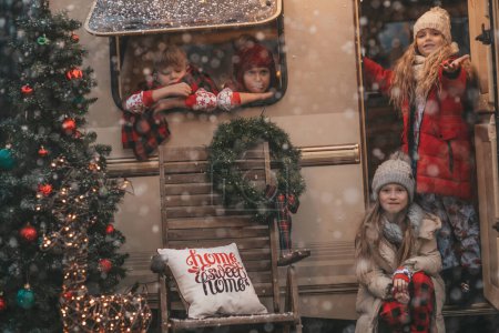 Photo for Children celebrating Christmas and New Year winter holidays season outdoor waiting Santa. Kids joyful spending time together near Xmas camper trailer rejoices at first snow enjoying childhood - Royalty Free Image